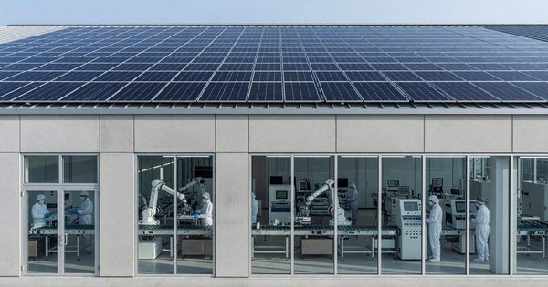 Solar panels on the roof of a modern manufacturing facility with clean production lines visible through large windows